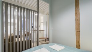 A bedroom with a bed, a wooden post, and a view of a bathroom. - Up to 6 people in the heart of Old Lyon (Lyon)