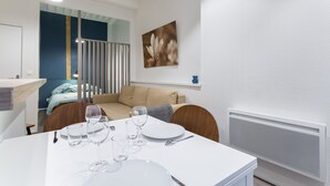 A modern dining area with a white table set for four, a sofa, and a radiator. - Up to 6 people in the heart of Old Lyon (Lyon)
