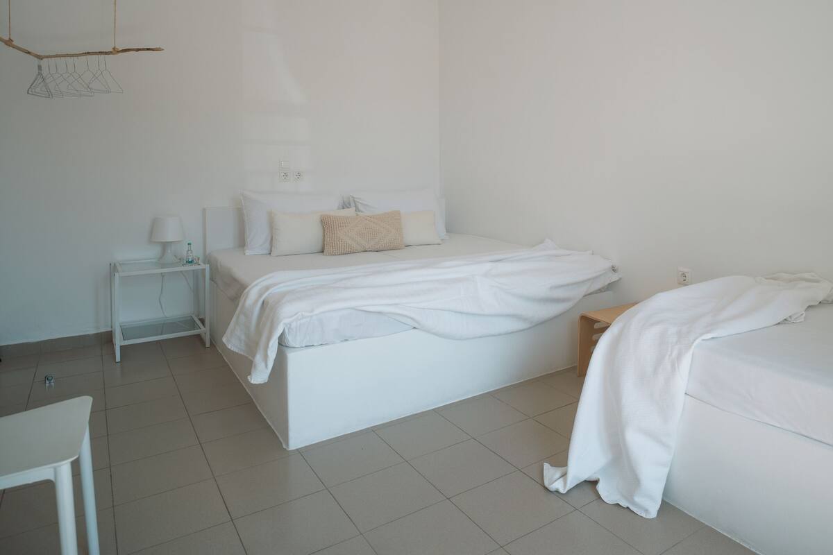 A minimalist bedroom with a bed, bedside table, and a small table with a lamp.
