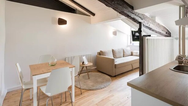 A modern loft-style living space with a dining area, a sofa, and a kitchen area. - Cozy cocoon on the heights of Old Lyon (Lyon)