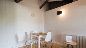 A dining area with a wooden table and white chairs, a small round table with a picture, and a wall clock. - Cozy cocoon on the heights of Old Lyon (Lyon)