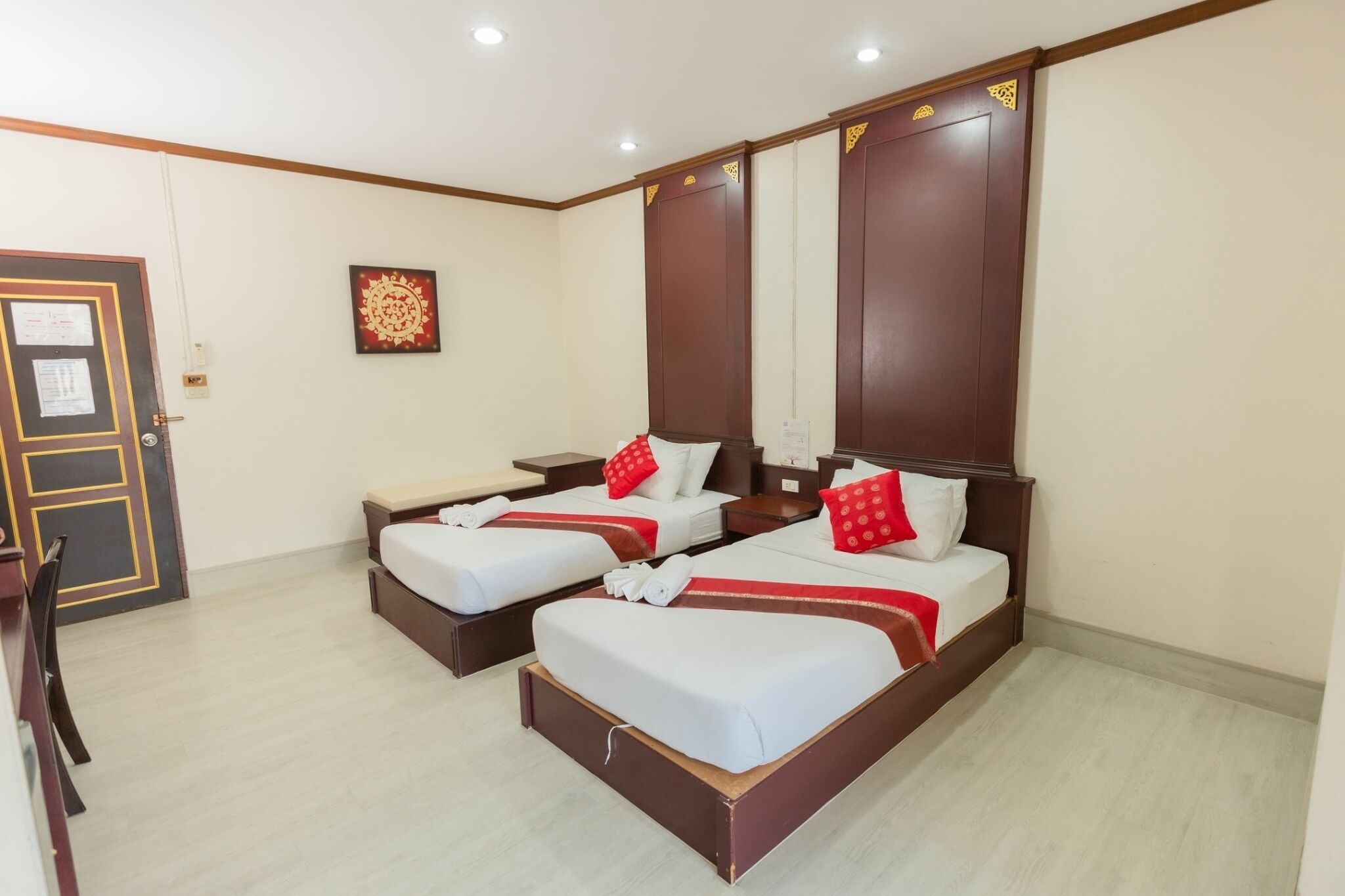 A hotel room with two single beds, a desk, and a chair.