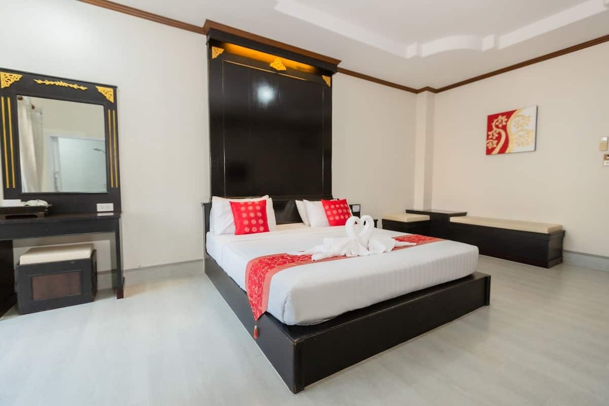 A modern hotel room with a large bed, a desk, and a mirror.