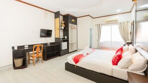 Una habitación de hotel con cama, escritorio, silla, televisor y ventana con cortinas.