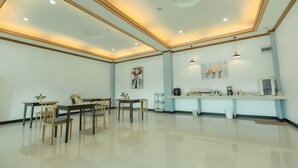 Una habitación amplia con una larga mesa de comedor, sillas, zona de cocina con electrodomésticos e iluminación empotrada en el techo.