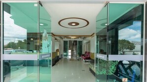 Un moderno vestíbulo de hotel con puertas de cristal, una escalera central y una recepción.