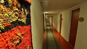 A hotel hallway with carpeted walls, doors, and a red floor. - Ylläs Lake hotel (Kolari)
