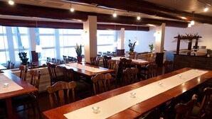 A restaurant with long wooden tables, chairs, and potted plants. - Ylläs Lake hotel (Kolari)