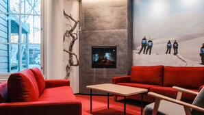 A modern interior with a red sofa, a small table, and a stone wall with a fireplace. - Hotel Ylläsrinne (Kolari)