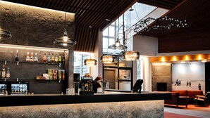 A bar area with a marble counter, shelves of liquor bottles, and hanging lights. - Hotel Ylläsrinne (Kolari)