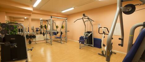 A gym with various exercise equipment, including a weight bench, a squat rack, and a cable machine.