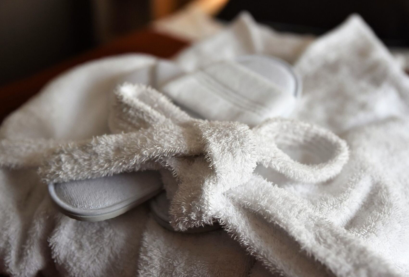 A white bathrobe with a fluffy texture and a metal clasp.