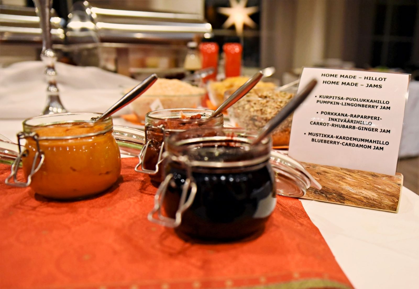 A table with jars of jam and a sign listing different flavors.