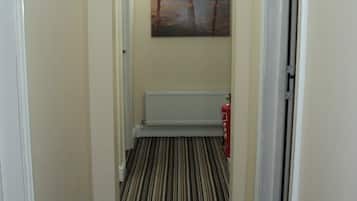 A narrow hallway with a striped carpet, a radiator, and a painting on the wall.