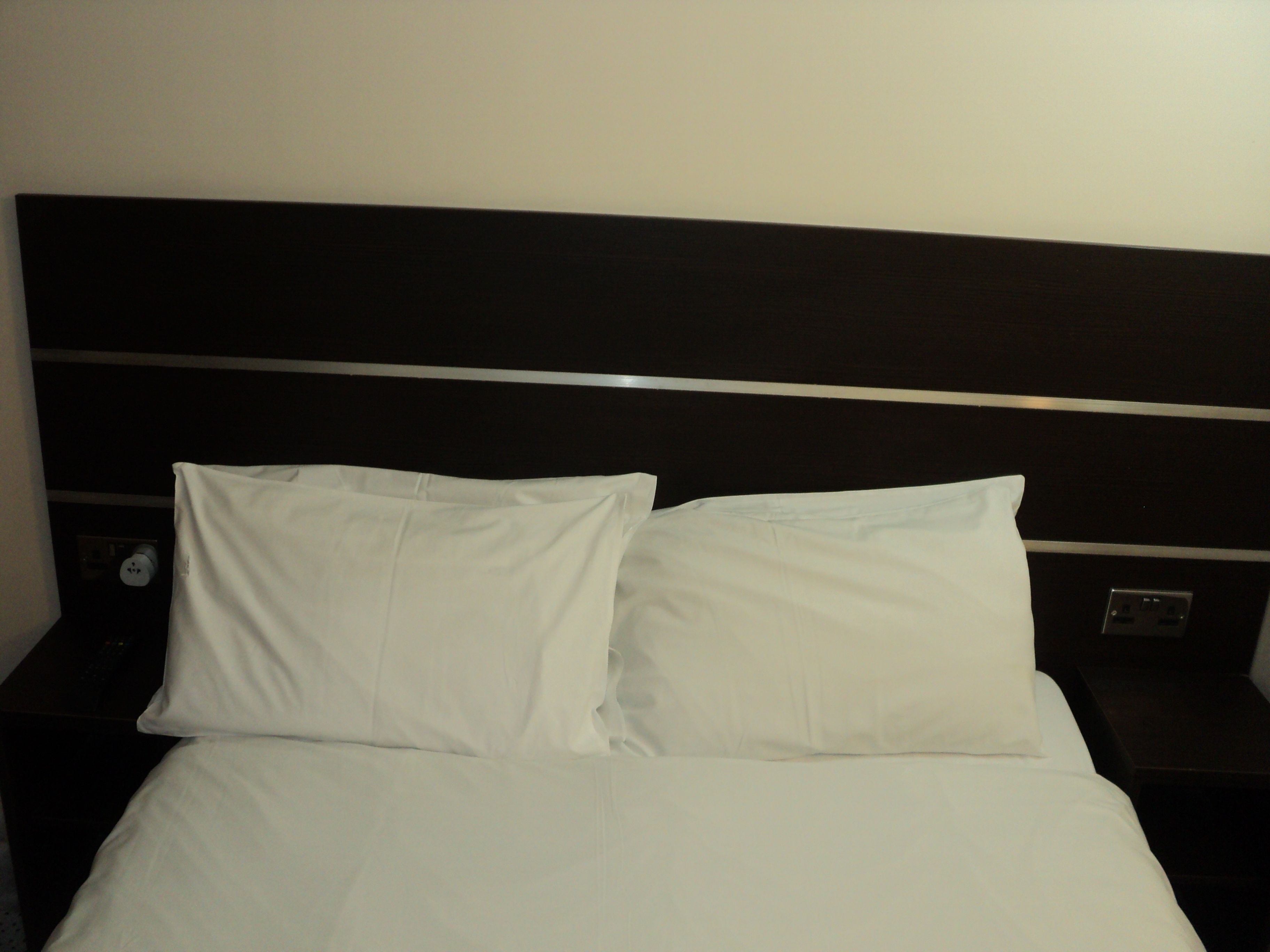 A bed with white linens and a dark headboard.