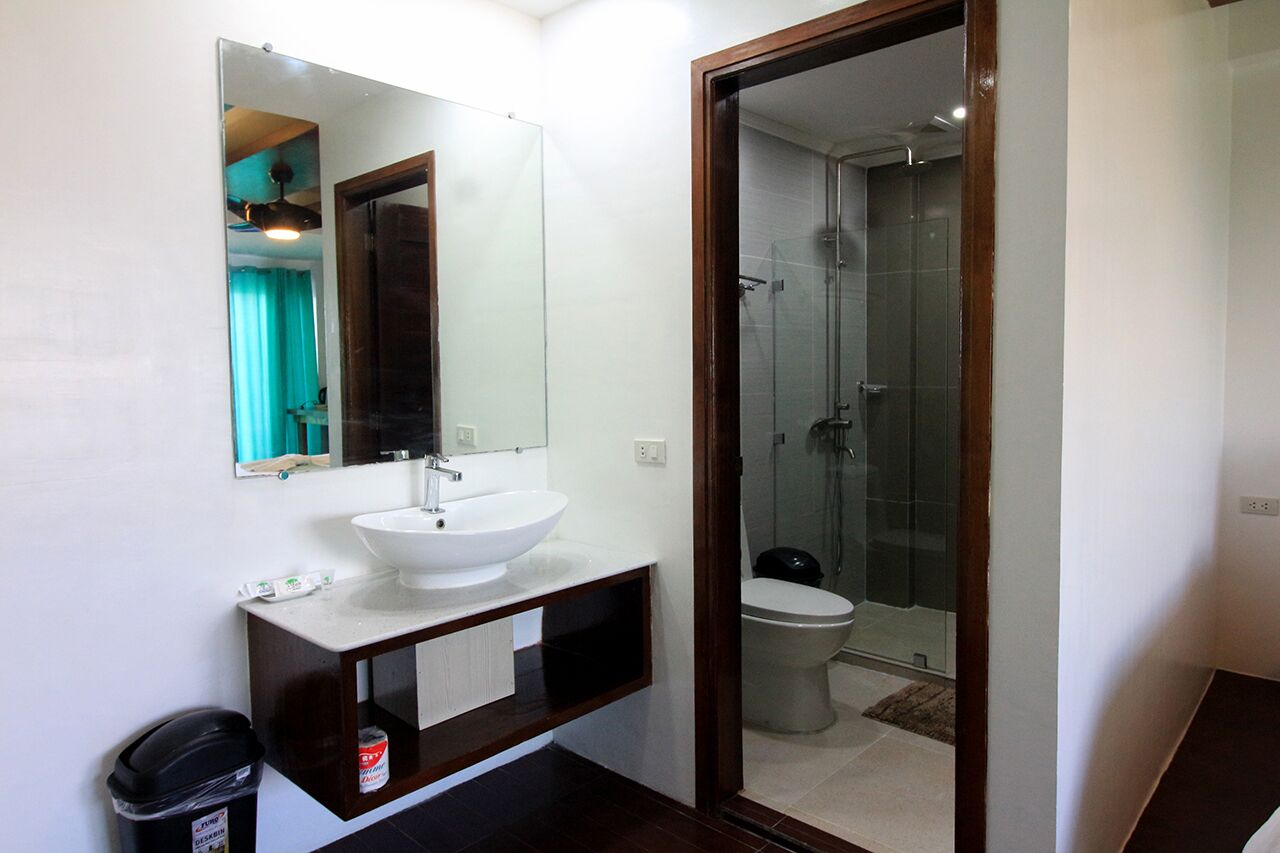 A bathroom with a white sink, mirror, and glass-enclosed shower.