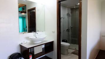 A bathroom with a white sink, mirror, and glass-enclosed shower.