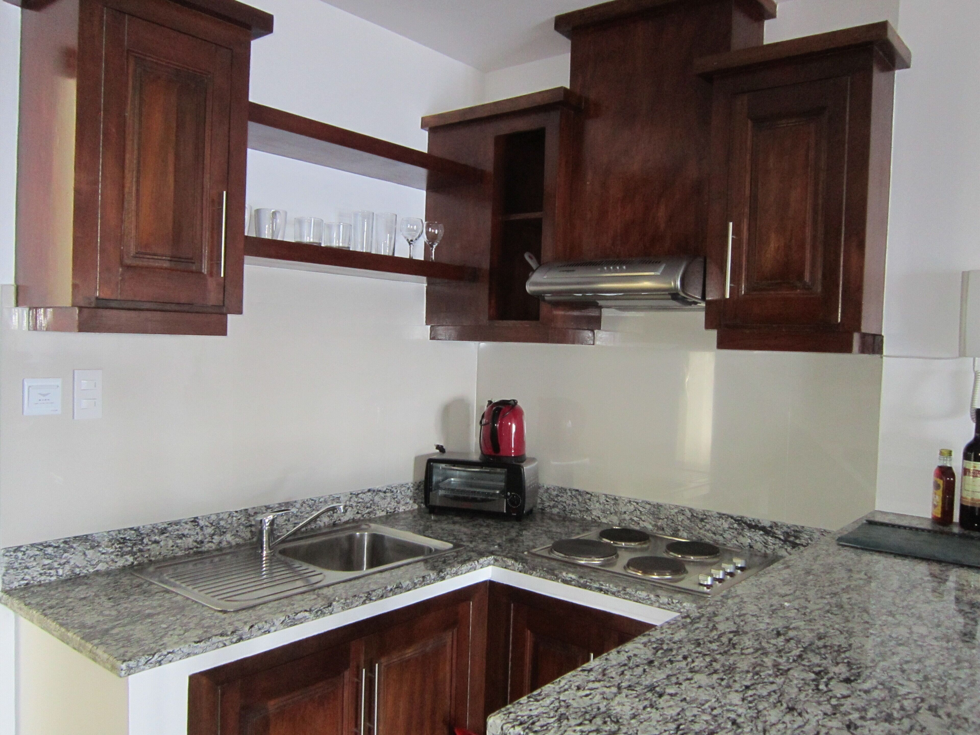 A kitchen with granite countertops, a stainless steel sink, a toaster, and wooden cabinets.