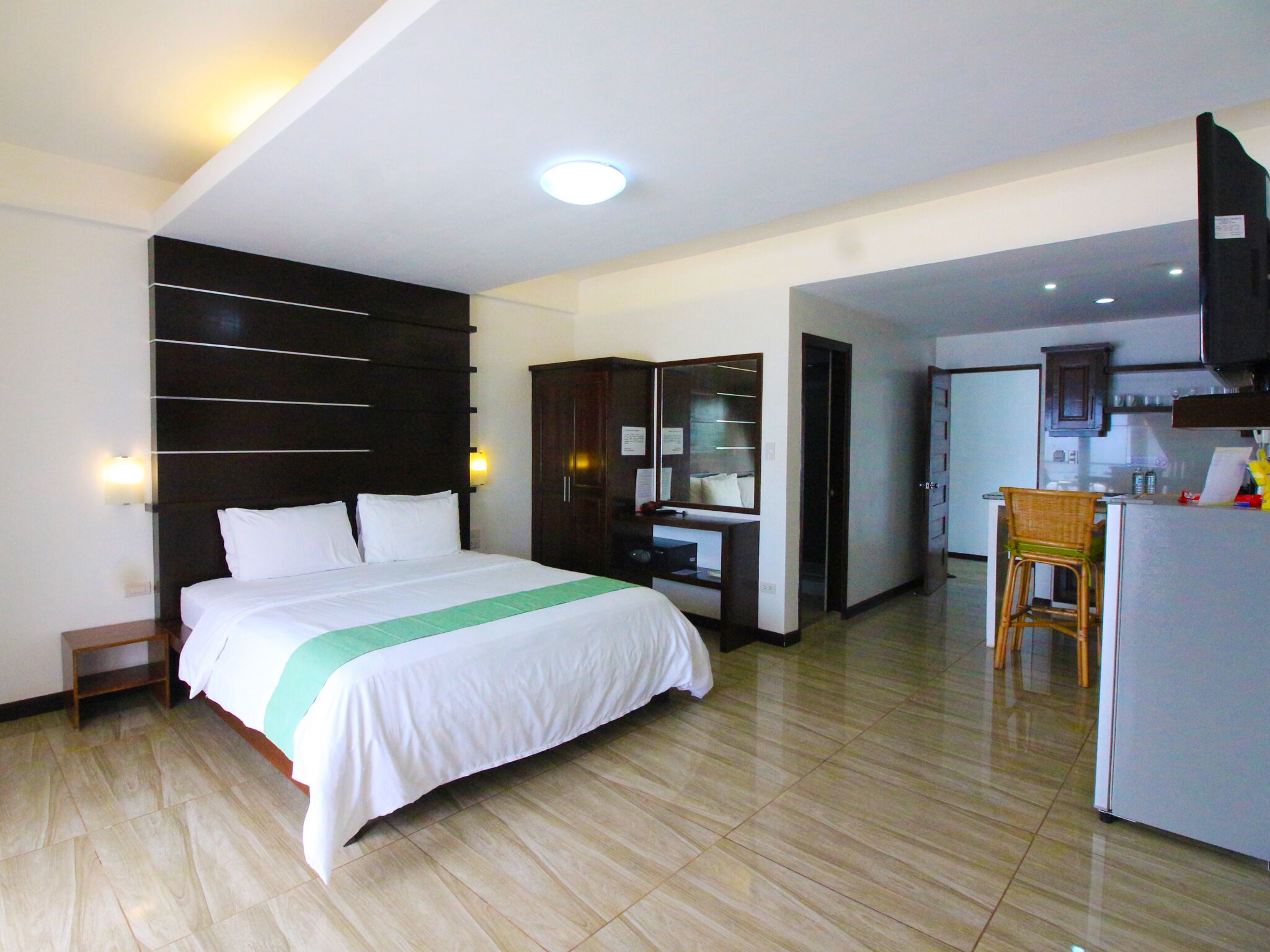 A hotel room with a bed, a desk, a chair, a wardrobe, and a television.