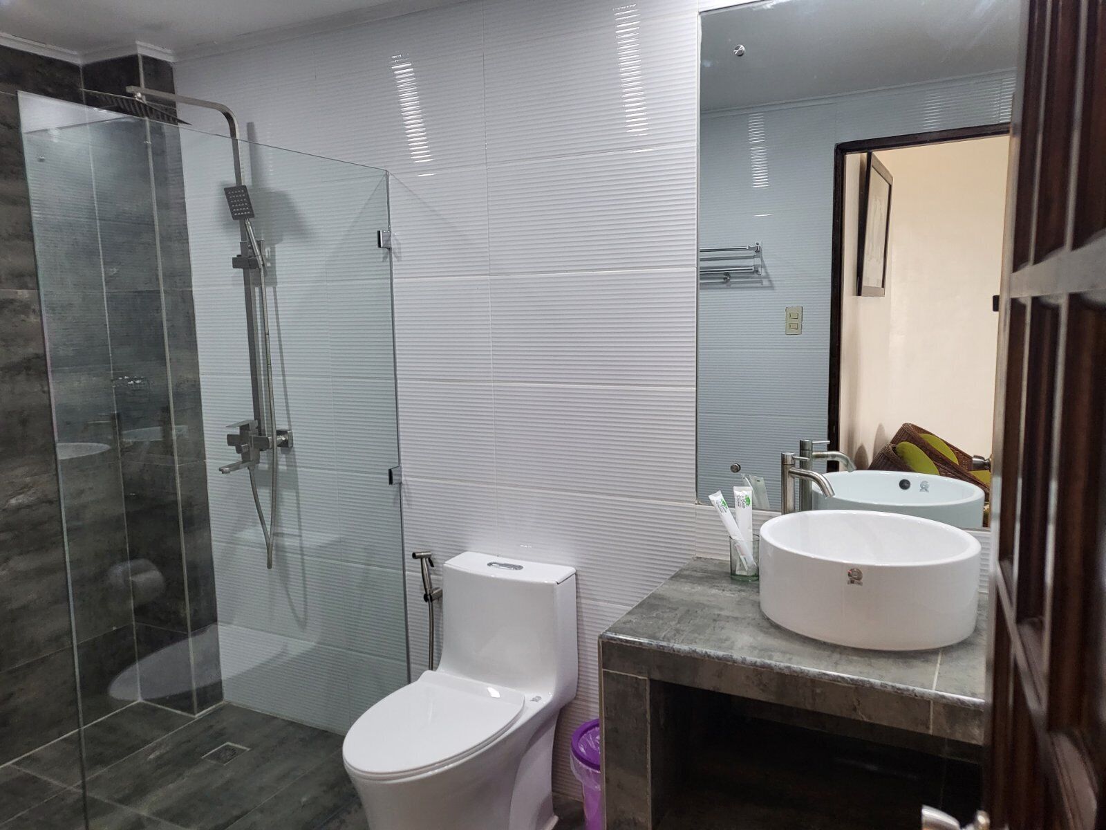 Un baño moderno con ducha de vidrio, un inodoro y dos lavamanos.