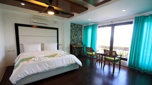 Une chambre d’hôtel avec un grand lit, une table à manger avec des chaises, une vue sur l’extérieur et un ventilateur de plafond.