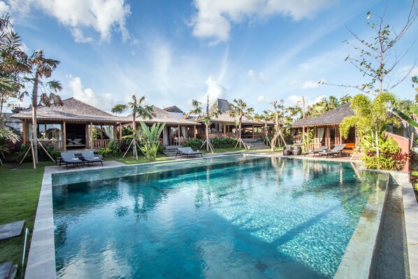 A swimming pool with lounge chairs and a tropical garden.