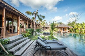 A resort with a pool, wooden deck, lounge chairs, and tropical plants. - Villa Sylvia (Kerobokan)