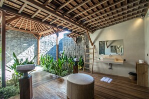 A modern bathroom with a stone wall, wooden beams, a sink, and a mirror.