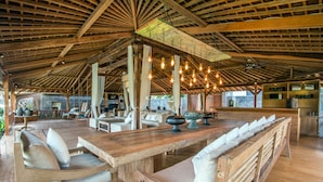 Un amplio espacio exterior para comer con mobiliario de madera y un techo alto.