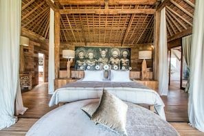 A spacious bedroom with a large bed, wooden ceiling, and a mural on the wall.