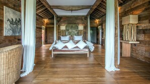 Una habitación rústica de madera con una cama grande, una silla de mimbre y un cuadro en la pared.