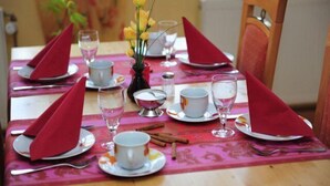 A dining table set with red napkins, white plates, and clear glasses. - Hotel Hirsch (Fulda)