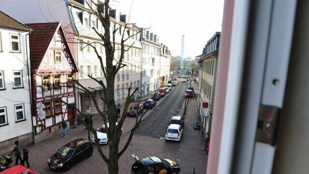 A street view with buildings, parked cars, and a tree. - Hotel Hirsch (Fulda)