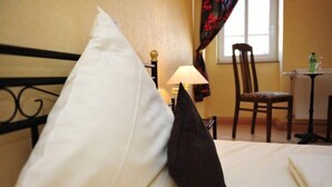 A hotel room with a bed, a chair, a table, and a window with curtains. - Hotel Hirsch (Fulda)