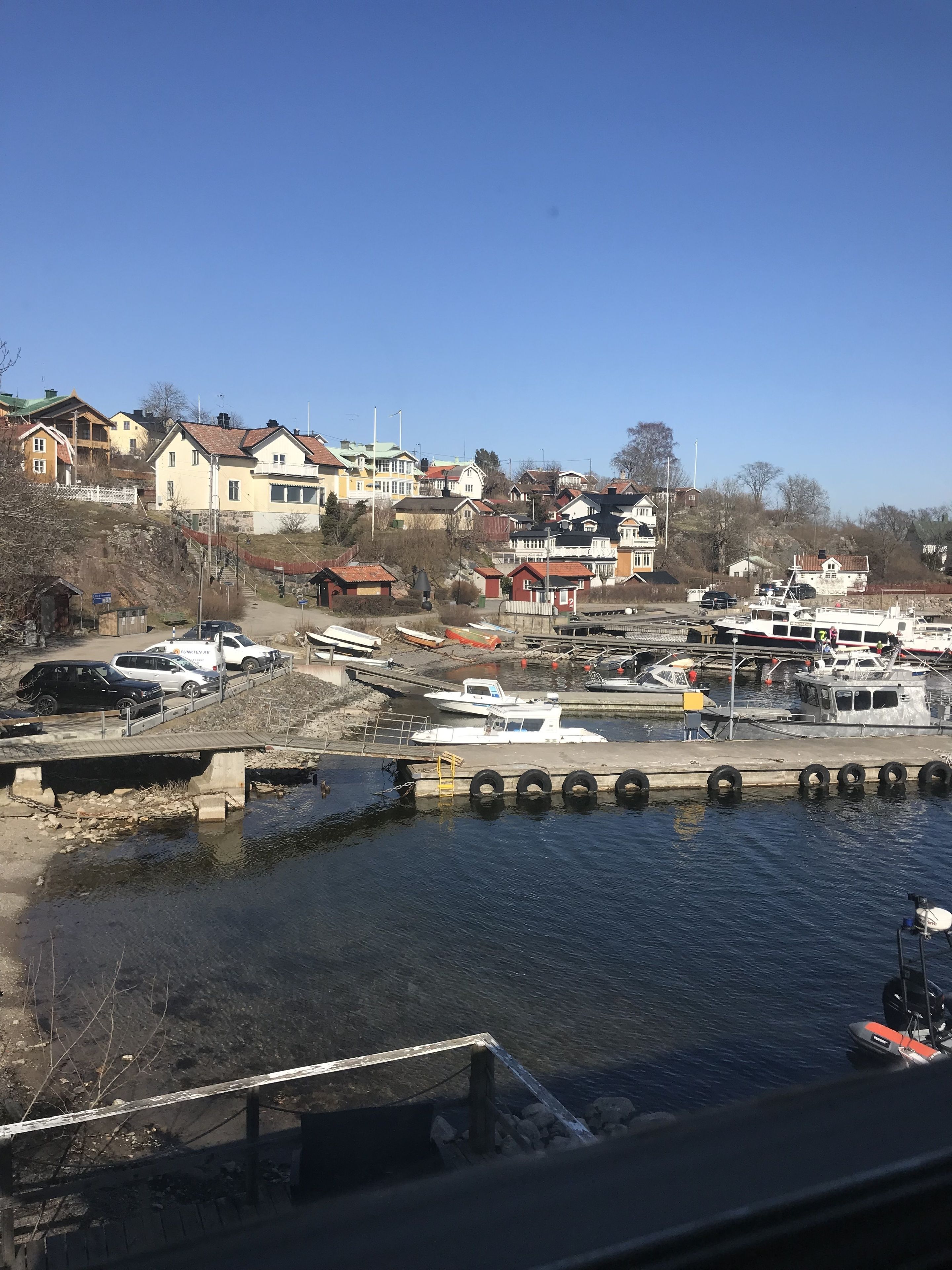 A marina with boats docked, a bridge, and residential buildings in the background.