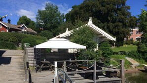 A wooden dock with a white gazebo, a small wooden structure, and a pond. - Hostel Lotsen (Dalaro)