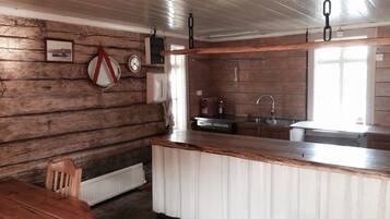 A rustic kitchen with wooden walls, a wooden dining table, and a built-in sink.