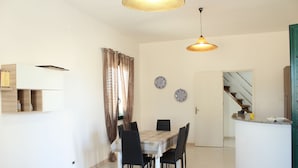 Un comedor con una mesa, sillas, una lámpara colgante y una escalera que lleva a otra habitación.