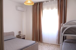 A bedroom with a bunk bed, a bedside table with a lamp, and a window with curtains. - La Zagara (Mazara del Vallo)