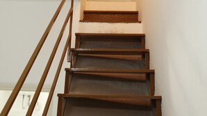 Una escalera de madera con barandilla que sube a un rellano.