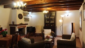A cozy living room with wooden beams, a fireplace, wicker furniture, and a television. - Villa Delle Ninfee (Mazara del Vallo)
