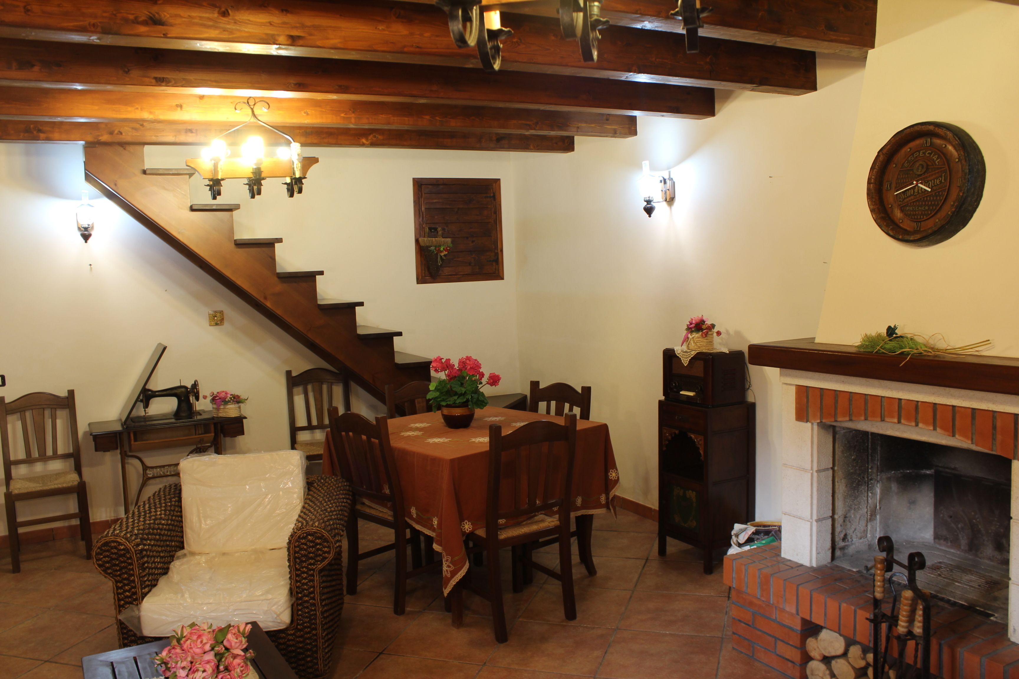 A dining area with a wooden table, chairs, a fireplace, and a staircase.