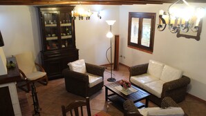A cozy living room with wicker furniture, a dining table with flowers, and a cabinet with glass doors. - Villa Delle Ninfee (Mazara del Vallo)