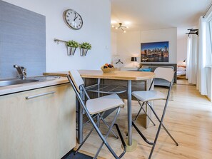 Een moderne keuken met een spoelbak, een klok en een eethoek met stoelen en een tafel.