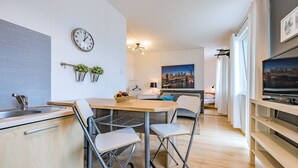 Une cuisine moderne avec un coin repas, un téléviseur et un tableau représentant un paysage urbain.