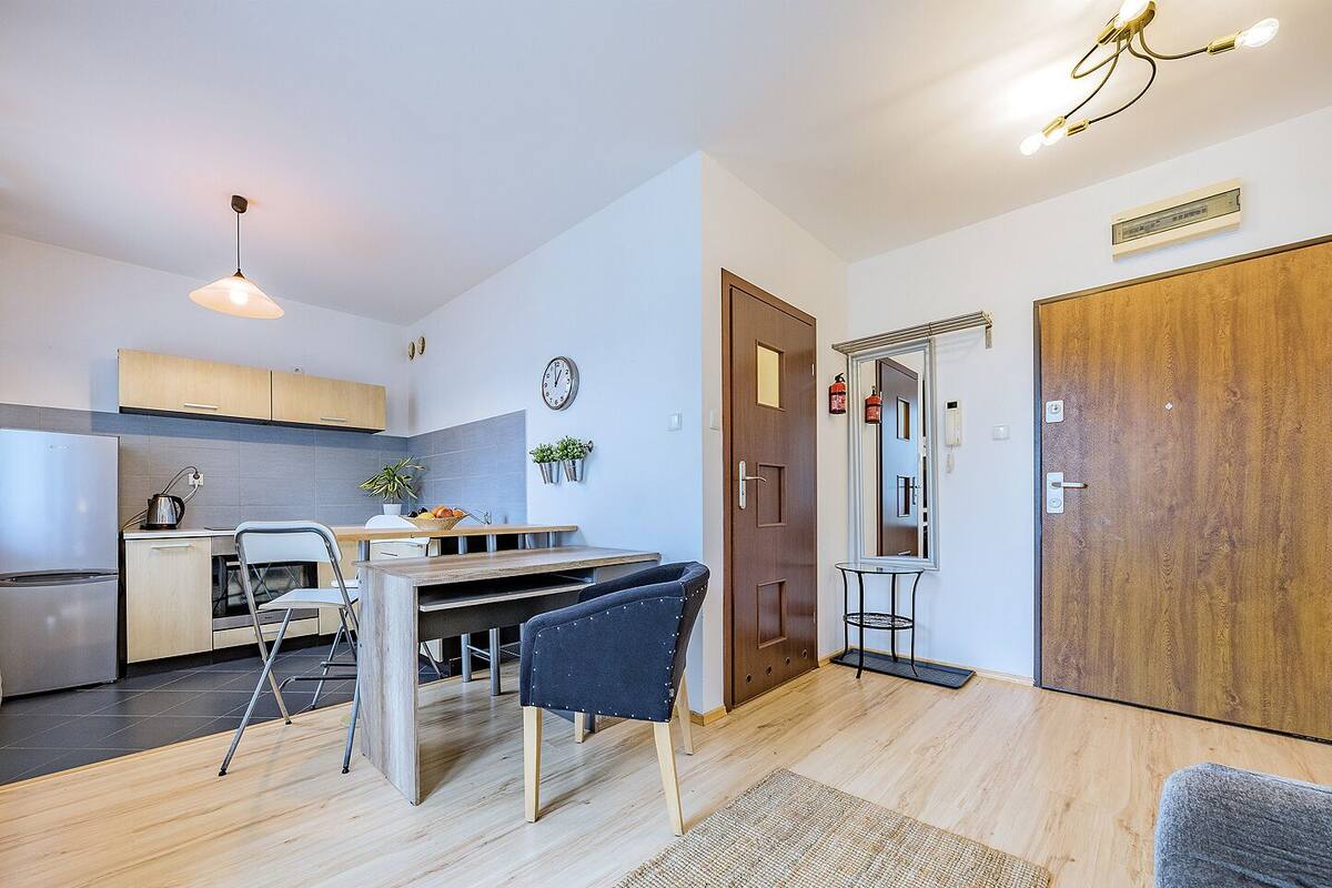 A modern kitchen with a dining area, a wooden door, and a small table with chairs.
