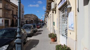 Una calle estrecha flanqueada por coches aparcados y edificios.