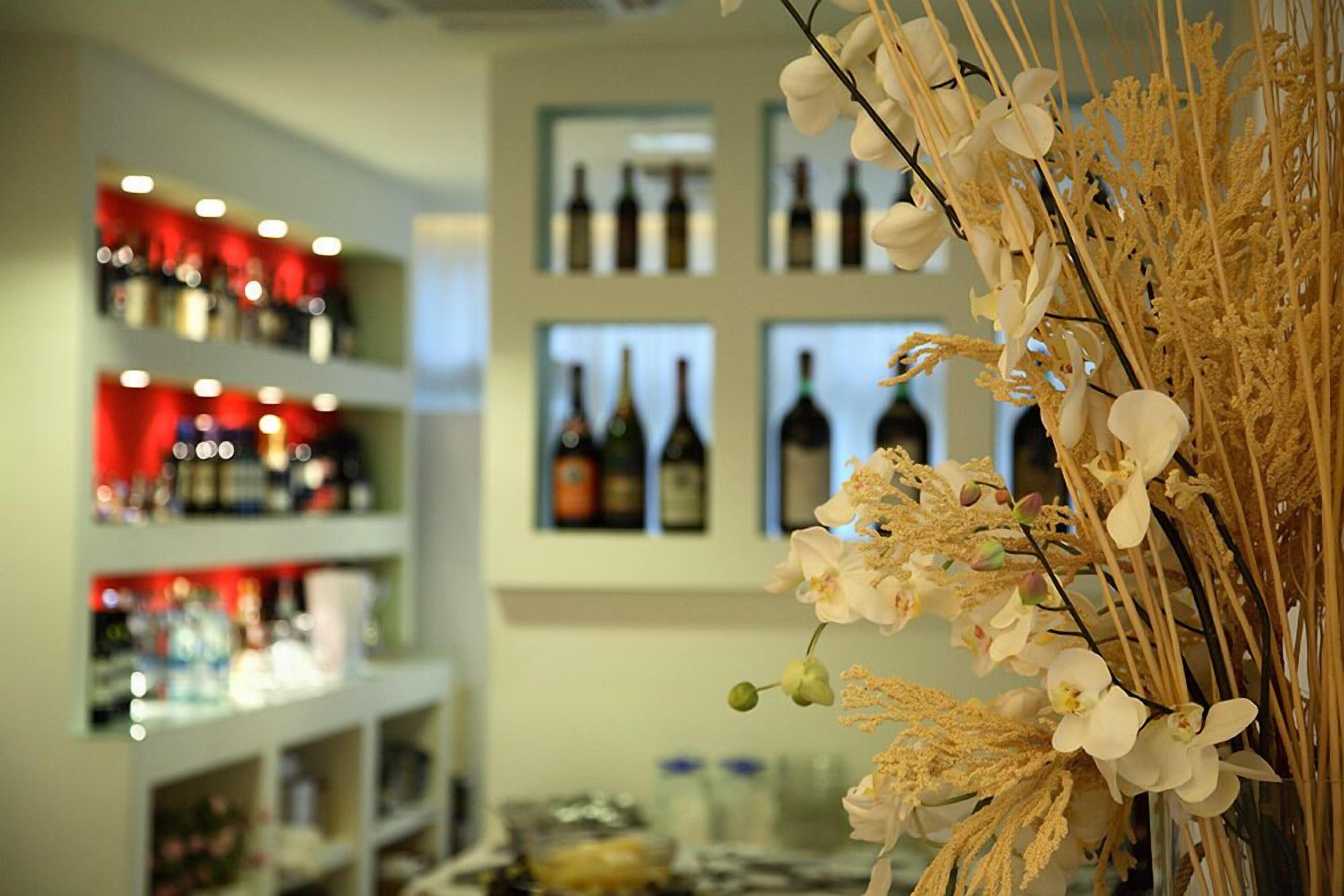 A bar area with shelves of bottles and a decorative arrangement of flowers.
