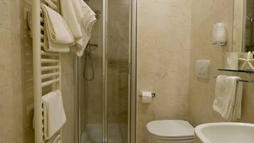 Een badkamer met douche, toilet en wastafel.