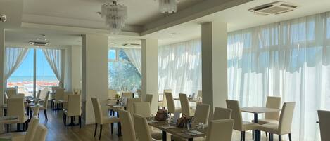 A spacious dining area with high ceilings, large windows, and elegant chandeliers.